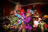 A man dressed as the Mad Hatter holding colourful feathers in front of a christmas tree