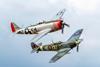 Two historic aeroplanes flying next to each other against blue sky