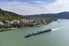 A long cruise ship sailing past a riverfront vilage