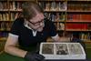 Three small drawings of the Bayeux Tapestry being looked at by a man in gloves