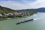 A long cruise ship sailing past a riverfront vilage