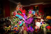 A man dressed as the Mad Hatter holding colourful feathers in front of a christmas tree