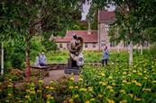 Three people looking at Henry Moore sculpture surrounded by gardens