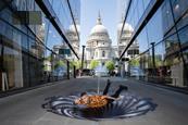 A man lies over an art installation of a vortex in front of St Paul's Cathedral