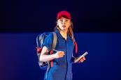 Young woman wearing red hat, blue boiler suit and holding note pad and pen