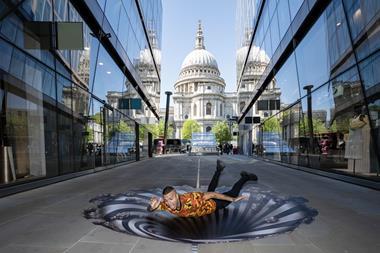 A man lies over an art installation of a vortex in front of St Paul's Cathedral