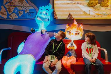 Two children sit with life-size sculptures from a pixar film