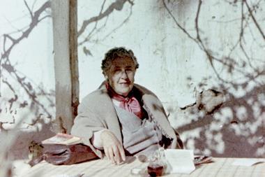 Agatha Christie sat at a table beneath a tree