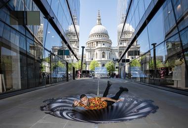A man lies over an art installation of a vortex in front of St Paul's Cathedral