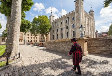 A Yeoman Warder at the Tower of London walking past the White Tower.