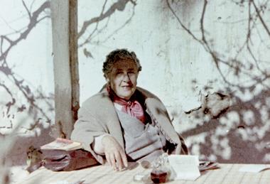 Agatha Christie sat at a table beneath a tree