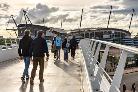 Fans walking across the bridge to the Etihad Stadium, home to Manchester City FC.