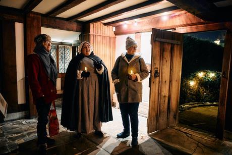 Costumed guide shows guests around Shakespeare's Birthplace Trust by candle light in Stratford-upon-Avon.