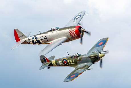 Two historic aeroplanes flying next to each other against blue sky