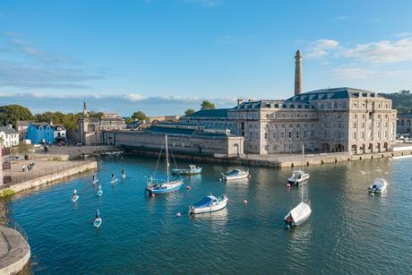 Boats and paddle boarders in the water next to the Royal William Yard in Portsmouth