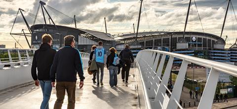 Fans walking across the bridge to the Etihad Stadium, home to Manchester City FC.