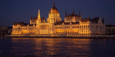 Hungarian Parliament Building lit up at night along the Danube river.