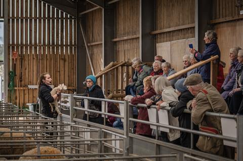 Visitors listen to a member of staff at Cotswold Farm Park in Gloucestershire who is holding a lamb
