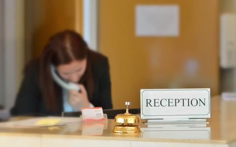 A receptionist on the phone at a hotel desk