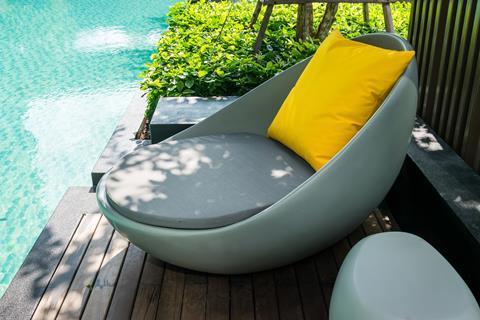Relaxing chairs with pillows beside swimming pool