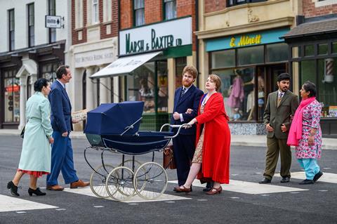 People dressed in 1950s clothing walk down a recreated high street at the Black Country Living Museum, Dudley