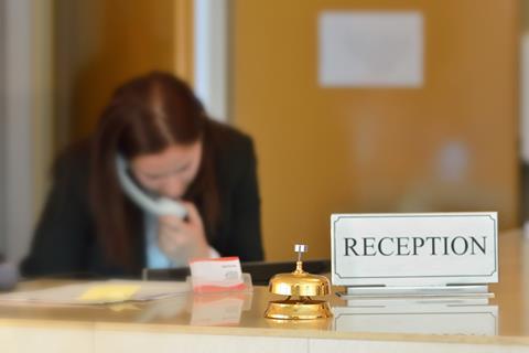 A receptionist on the phone at a hotel desk