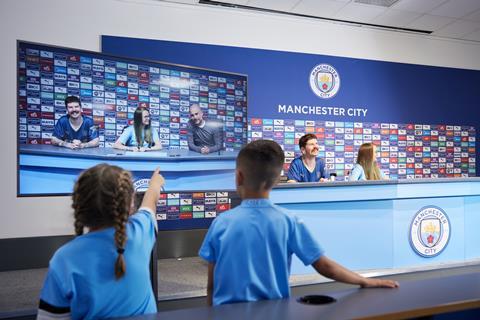 A group taking part in the Manchester City Stadium tour with a virtual Pep Guardiola