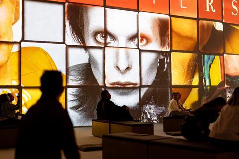 People sat in front of a screen depicting David Bowie's face