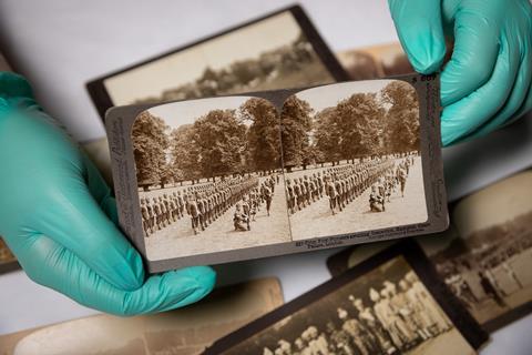 A curator handles old photographs on display as part of The Indian Army at the Palace exhibition at Hampton Court Palace