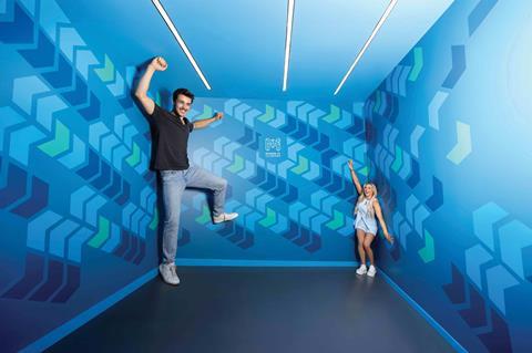 Man and woman in illusion room that makes man look giant and woman look tiny