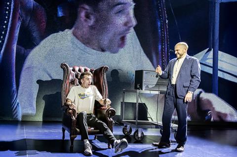 Man in chair looks shocked while another man grimaces at him during stage show