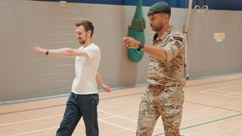 Royal Marine showing a man in a white t shirt how to march
