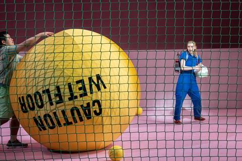 Man rolling huge yellow ball onto stage
