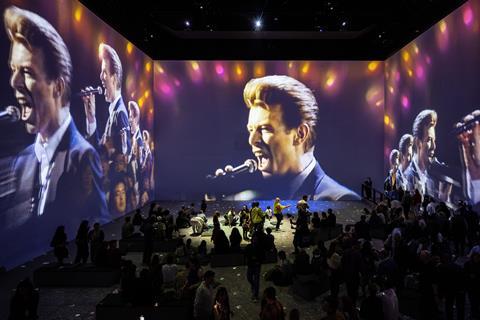 Audience watches David Bowie performance on large screens around room