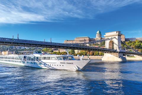A long cruise ship sails under bridge in european city
