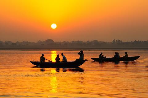 People on boat in India during sunset.