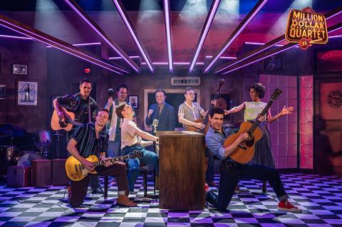 Eight cast members on stage playing various instruments performing
