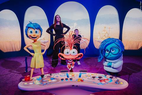 An adult and child stand behind sculptures of characters from Inside Out