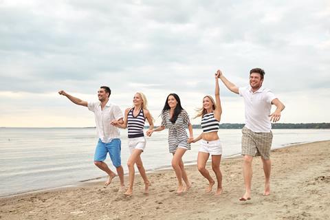 Happy group of people walking on the beach