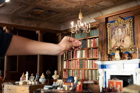 A Royal Collection Trust curator tweaks the display in Queen Mary's Dolls House at Windsor Castle