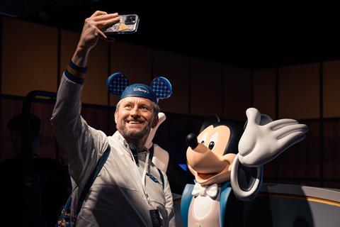 Man taking a selfie with Mickey Mouse at the Disney100: The Exhibition