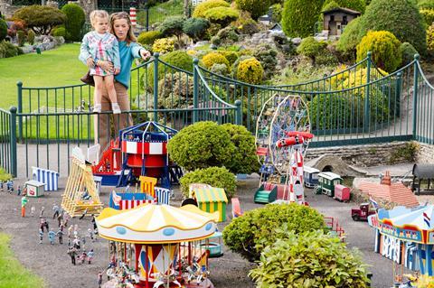 A woman and child looking at a model village fairground